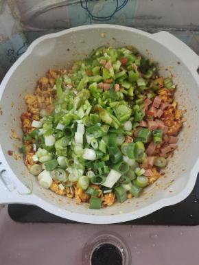 放入青椒丁，火腿肠丁，葱末翻炒片刻！