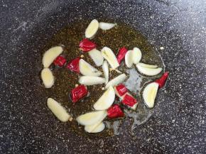 锅里继续倒油烧热，下入蒜片和干红辣椒爆香。 