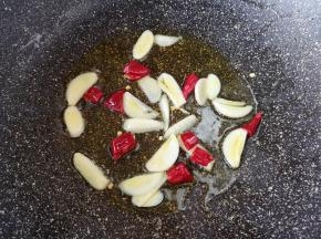 锅里继续倒油烧热，下入蒜片和干红辣椒爆香。 