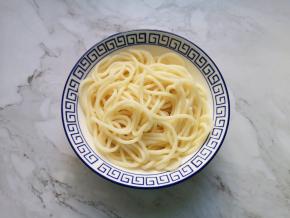 过过凉水的面条捞入碗里。 