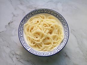 过过凉水的面条捞入碗里。 