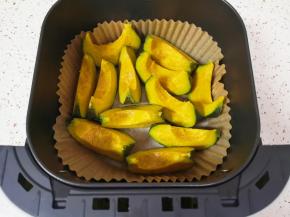 空气炸锅炸篮里放上专用油纸，放入切好的贝贝南瓜，刷上一层橄榄油。