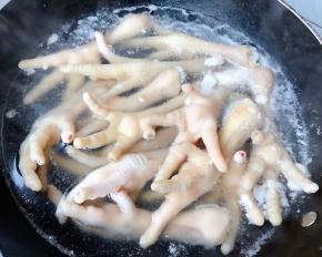 锅中烧开水倒入料酒放入凤爪焯水断生去除杂质和多余的油脂