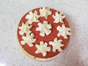 继续放上第二层蛋糕片，抹上一层奶油，放上草莓丁，用裱花袋里的奶油继续在蛋糕边上挤出奶油花，放上最后一片蛋糕，挤上几朵奶油花。
