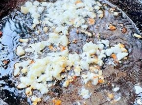 另起锅倒入底油加热放入蒜粒爆香