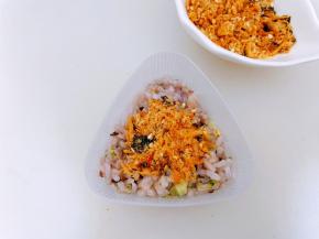 饭团模具里先放入一些米饭铺平，中间铺上肉松再盖上米饭