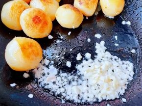 小土豆两面煎至金黄色移到一侧，放入蒜粒爆香。