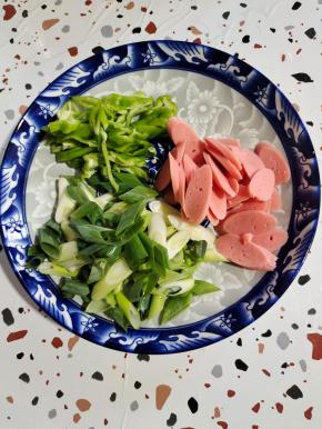 火腿肠切成片，青椒切成丝，葱切成段备用！