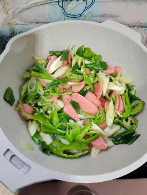 起锅烧油，放入火腿肠，青椒，葱炒软！