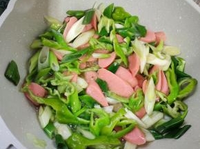 起锅烧油，放入火腿肠，青椒，葱炒软！