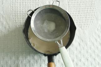 慢慢倒入打好的蛋黄糊中，边倒边搅拌，搅打均匀后过筛回不粘锅里。