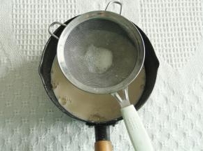 慢慢倒入打好的蛋黄糊中，边倒边搅拌，搅打均匀后过筛回不粘锅里。
