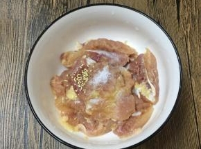 鸡腿去骨去皮，用刀背剁一剁然后切块，放入碗中，调入盐和鸡精。