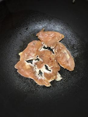 锅里倒入少许油，大火加热，放入腌好的鸡胸肉，中火煎至金黄色。