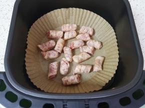 空气炸锅炸篮里铺上专用油纸，放上香肠。 