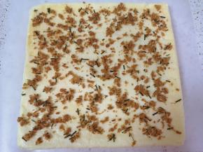 取一张更大的油纸，将蛋糕片翻面，抹上一层沙拉酱，撒上肉松。 