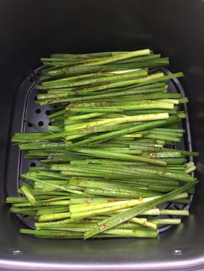 将韭菜摆入预热好的空气炸锅中，刷上刚才调好的酱料。