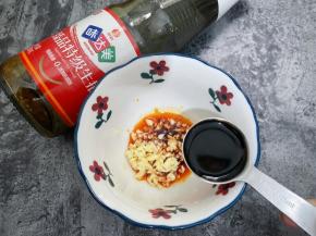 碗里加入红油辣椒，蒜末和味达美臻品特级生抽