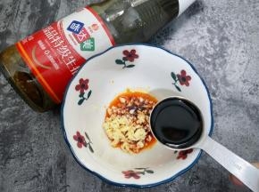 碗里加入红油辣椒，蒜末和味达美臻品特级生抽