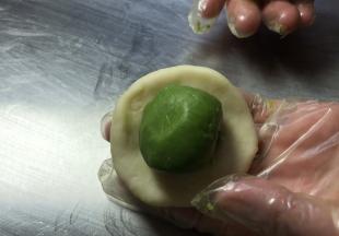 取水油皮面团收口朝上擀成薄饼皮，放入酥油皮面团，包裹严实