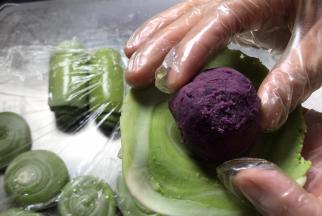 取出冷藏的紫薯蛋黄馅，放在饼皮里，包裹严实