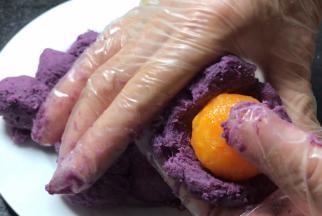 取出紫薯馅分成14份，按成饼状，放入蛋黄包裹严实，放冰箱冷藏备用