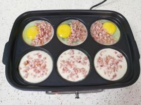 六圆盘一边打入鸡蛋，撒上一些培根碎，一边倒入调好的面糊，撒上一些培根碎。