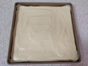 烤盘里铺上油纸，倒入蛋糕糊，轻震几下震出大气泡，用刮刀刮平表面。