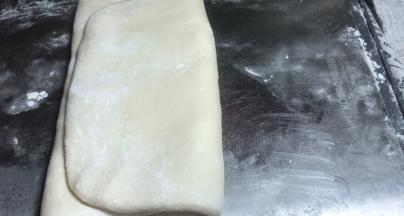 再将面皮的一头向中间折放，将另一头盖住成三层的面饼