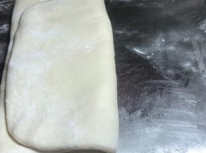 再将面皮的一头向中间折放，将另一头盖住成三层的面饼