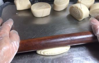 取小剂子侧卧按压 ，擀成薄面皮