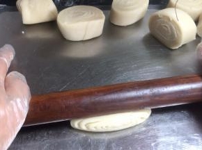 取小剂子侧卧按压 ，擀成薄面皮