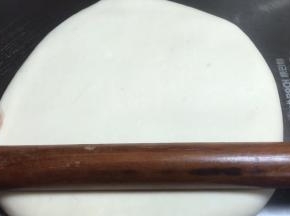 倒扣在案板上，用擀面杖轻轻按压成饼，再慢慢擀成长方形面皮
