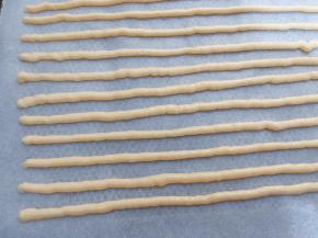 裱花袋剪一个小口，再铺有油纸的烤盘上挤出长条