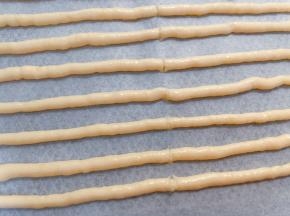 完全挤完后用刮刀从中间切一刀，方便后面分段
放入预热好的烤箱中层先180度烤10分钟膨胀定型，再转150度烤15分钟左右变脆