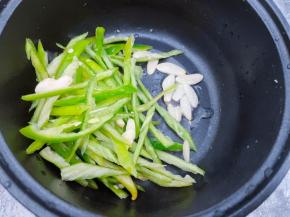 锅里再放入少许植物油，下入蒜片爆香后加入青椒丝翻炒至断生