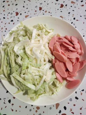 火腿肠切成片，包菜切成丝备用！