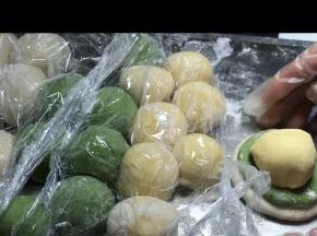 取第一个揉的白色面团按扁，再取第一个揉好的绿面团按扁，放入白色上面，再取第一个揉好的黄色面团放在绿色上面