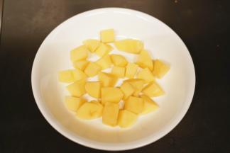 土豆去皮后切成小方块，放入盘底