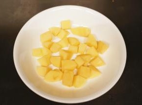 土豆去皮后切成小方块，放入盘底