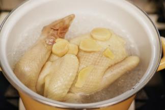 锅里烧开水后放入洗净的老母鸡焯去血水，焯水时加入几片姜片