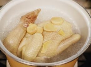 锅里烧开水后放入洗净的老母鸡焯去血水，焯水时加入几片姜片