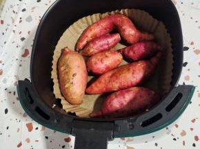 空气炸锅里铺一张油纸盘，把清洗干净的红薯摆放在里面！