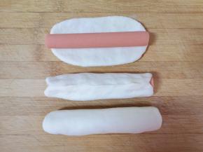 留下三分之一的面团分成三分，擀成长条状包入火腿肠，如图。