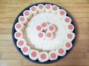 将小段火腿肠在披萨盘周围摆一圈，中间也摆出一朵小花。