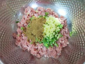 将肉馅放入盆里，加入切碎的大葱和生姜，放上十三香。