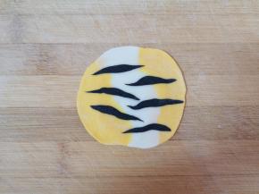 将黑色的小条随意摆放在饺子皮上，用擀面杖来回擀一下，一张虎皮饺子皮就做好了。