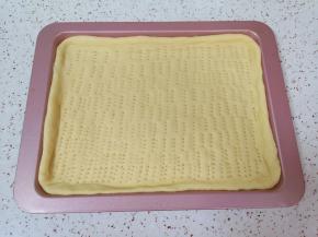 擀成比烤盘稍微大一点的面片放入烤盘，用叉子扎上小孔，防止饼皮在烤制的过程中凸起。