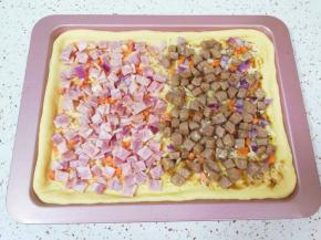 撒上一半洋葱和胡萝卜碎，抹番茄酱的一边铺上培根肉，抹黑胡椒酱的一边铺上煎好的牛排。