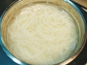 把煮好的过桥米线倒入滤水盆里，用清水冲一下